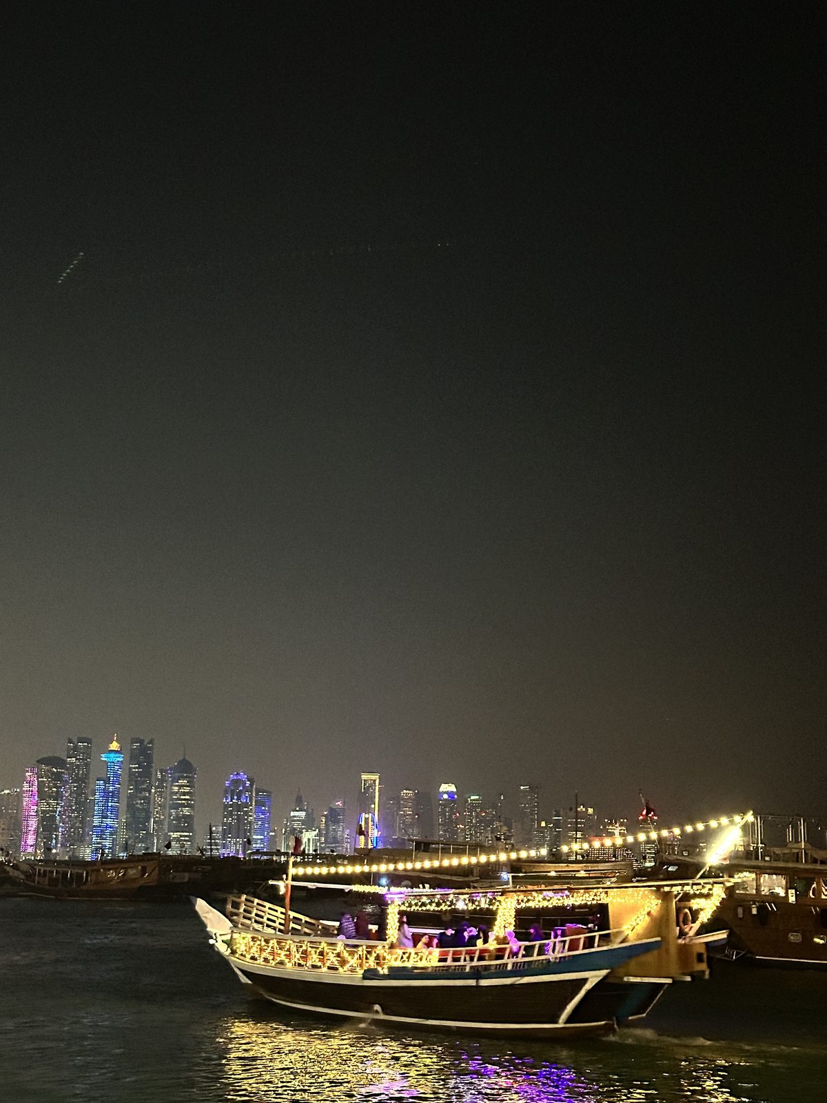 Dhows lit up in front of the West Bay skyline at night, Doha
