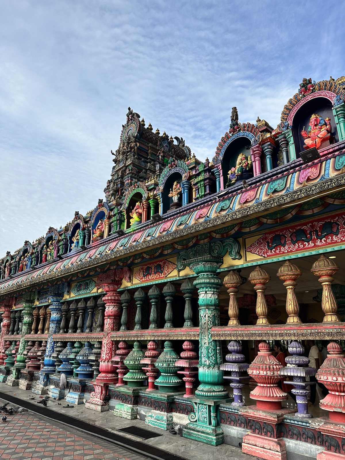 The multicoloured Dravidian gopuram and painted colonnade of the temple at Batu Caves against a morning sky