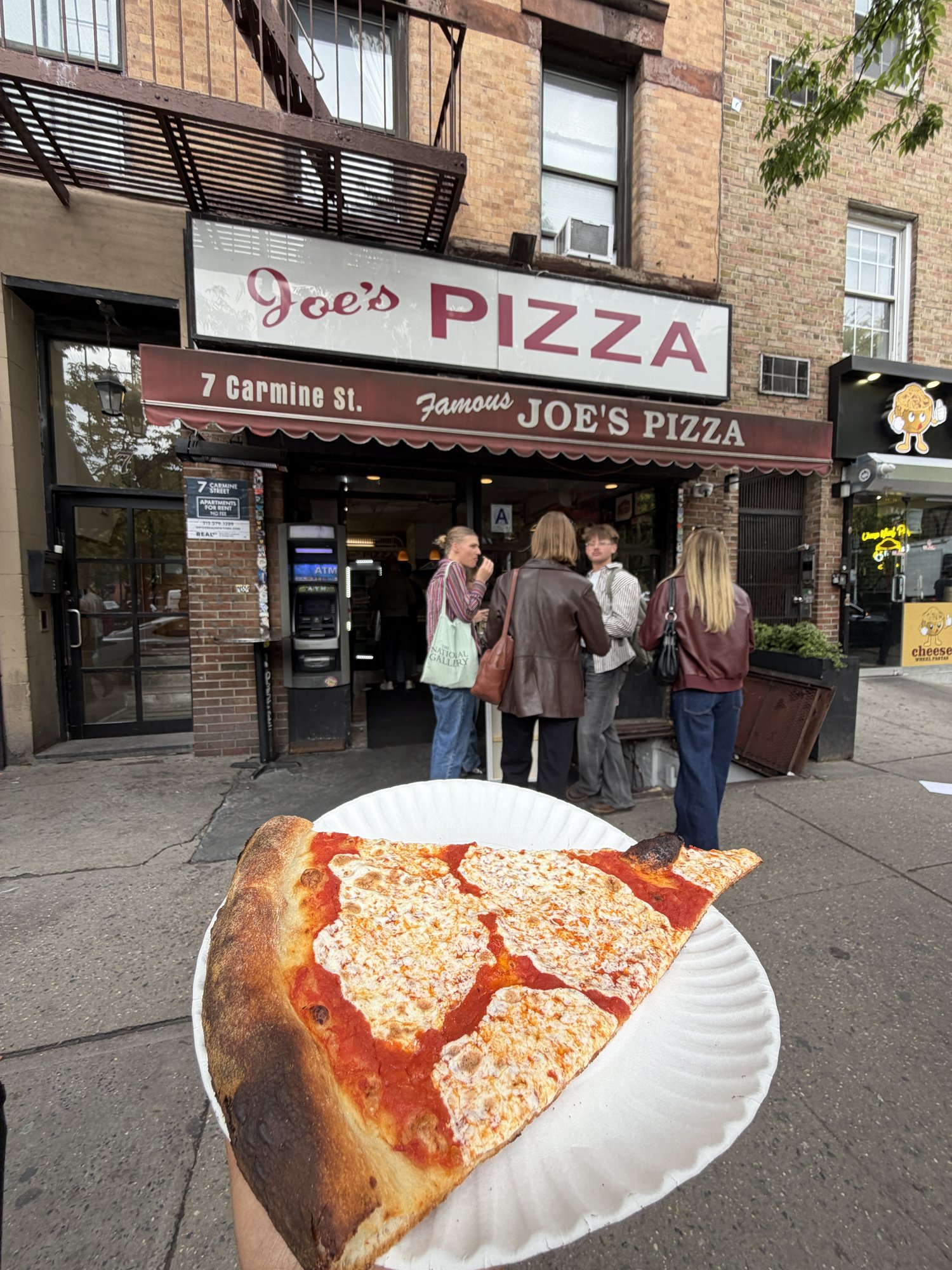 A slice of pizza outside Joe’s Pizza in New York