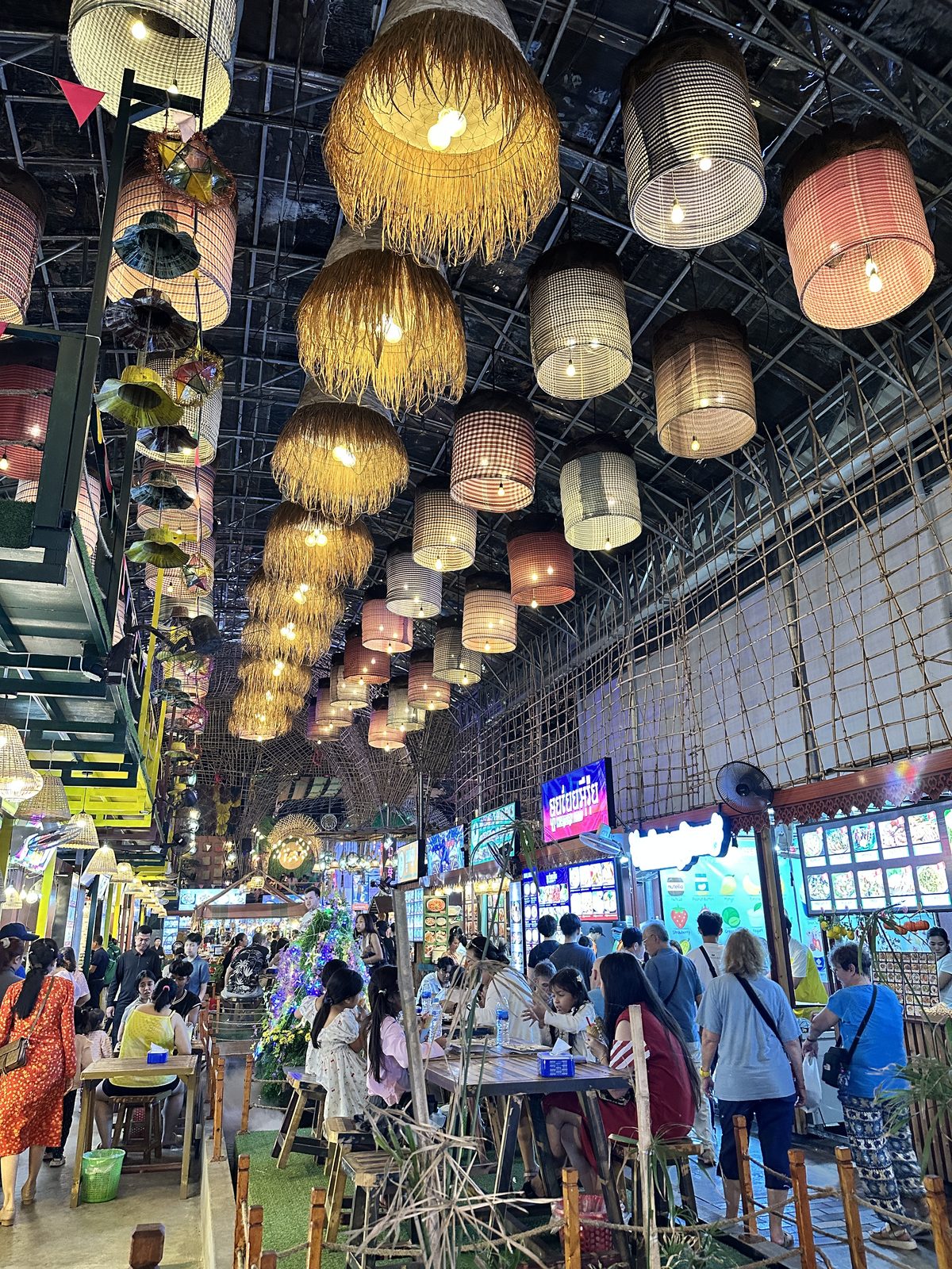 A covered night market in Siem Reap with dozens of woven basket lampshades hanging from the ceiling above food stalls