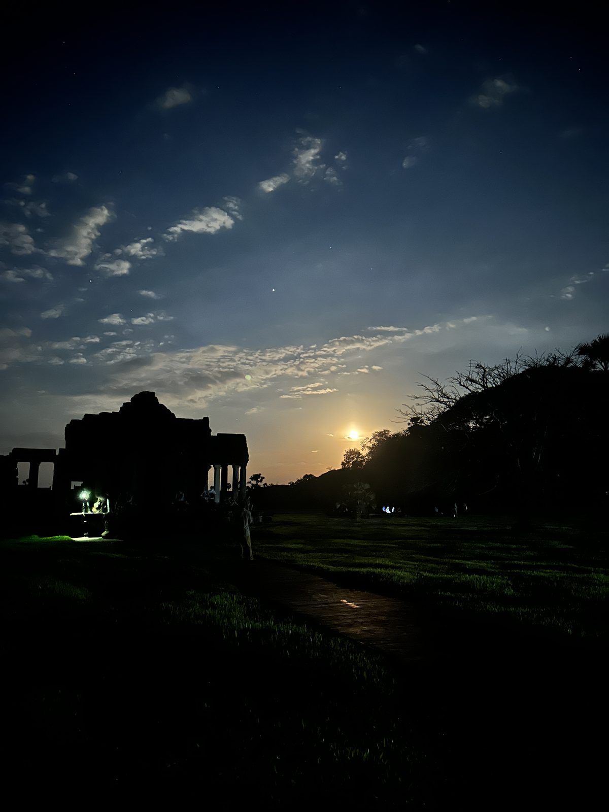 A temple building in near-darkness before dawn, with the last of the moonlight in the sky above