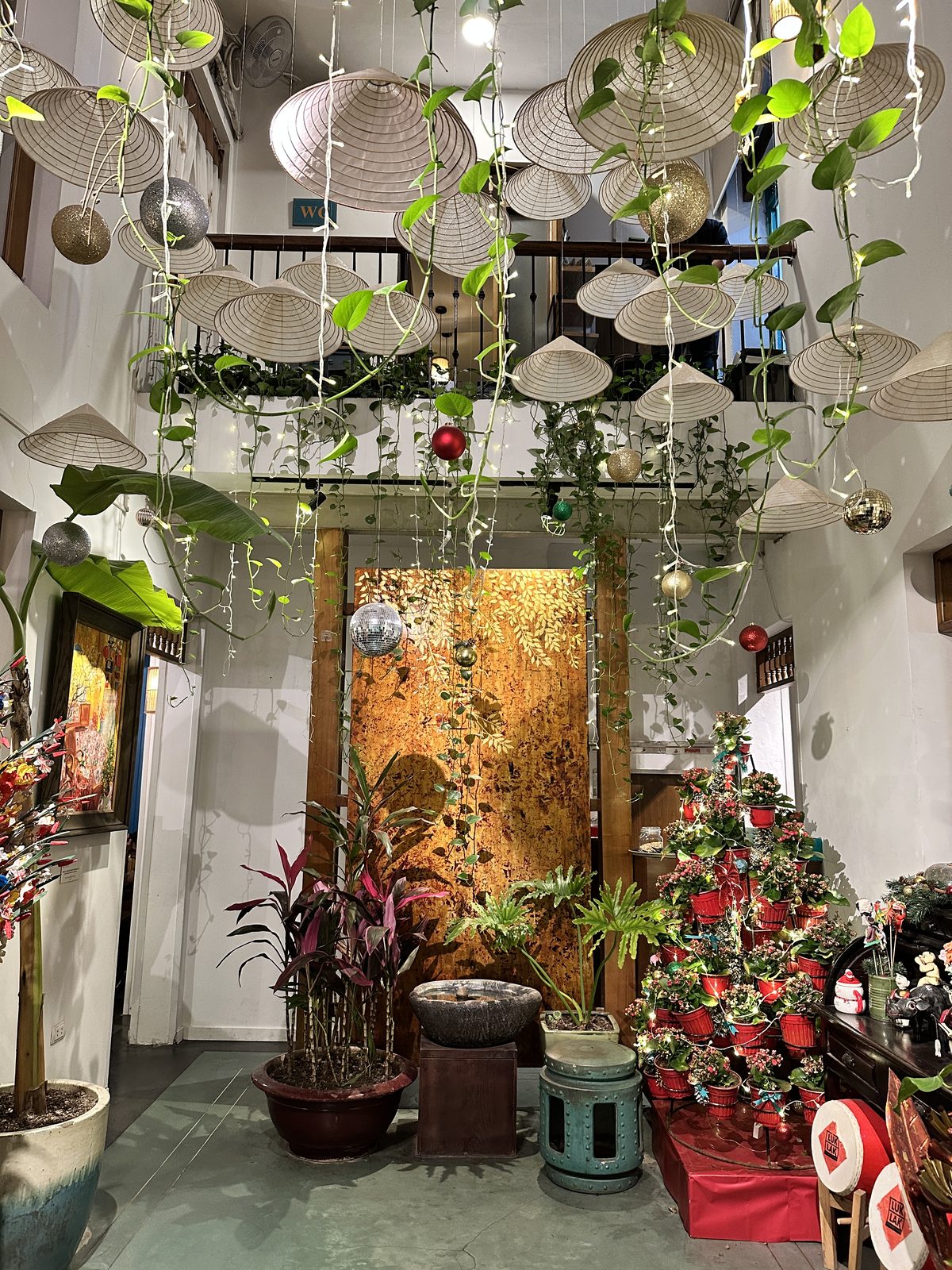 The interior of Luk Lak, with conical hats and trailing vines hanging from a double-height ceiling