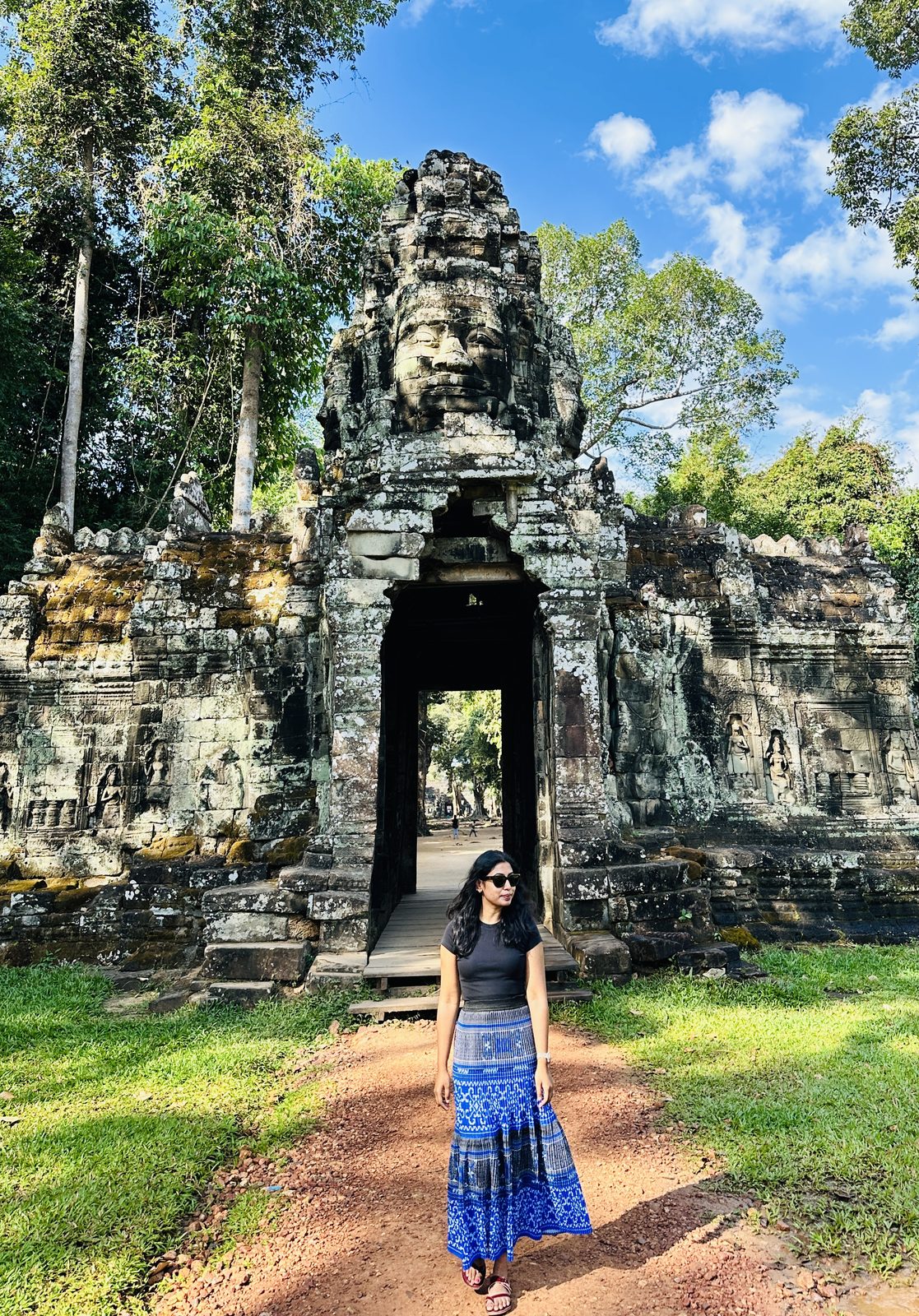 A stone gateway topped with a carved four-faced tower, surrounded by jungle
