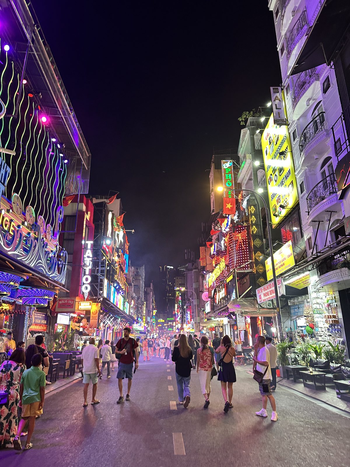 Bui Vien walking street in Saigon at night, packed with neon signs and crowds
