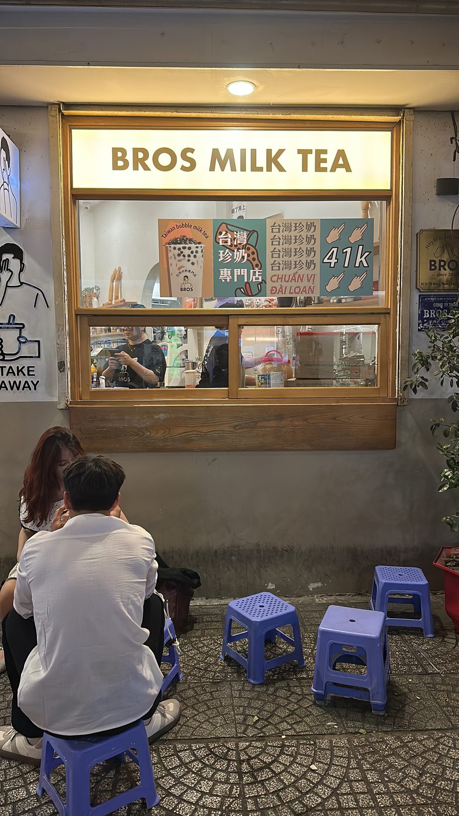 A bubble tea kiosk in Saigon with blue plastic stools out on the pavement