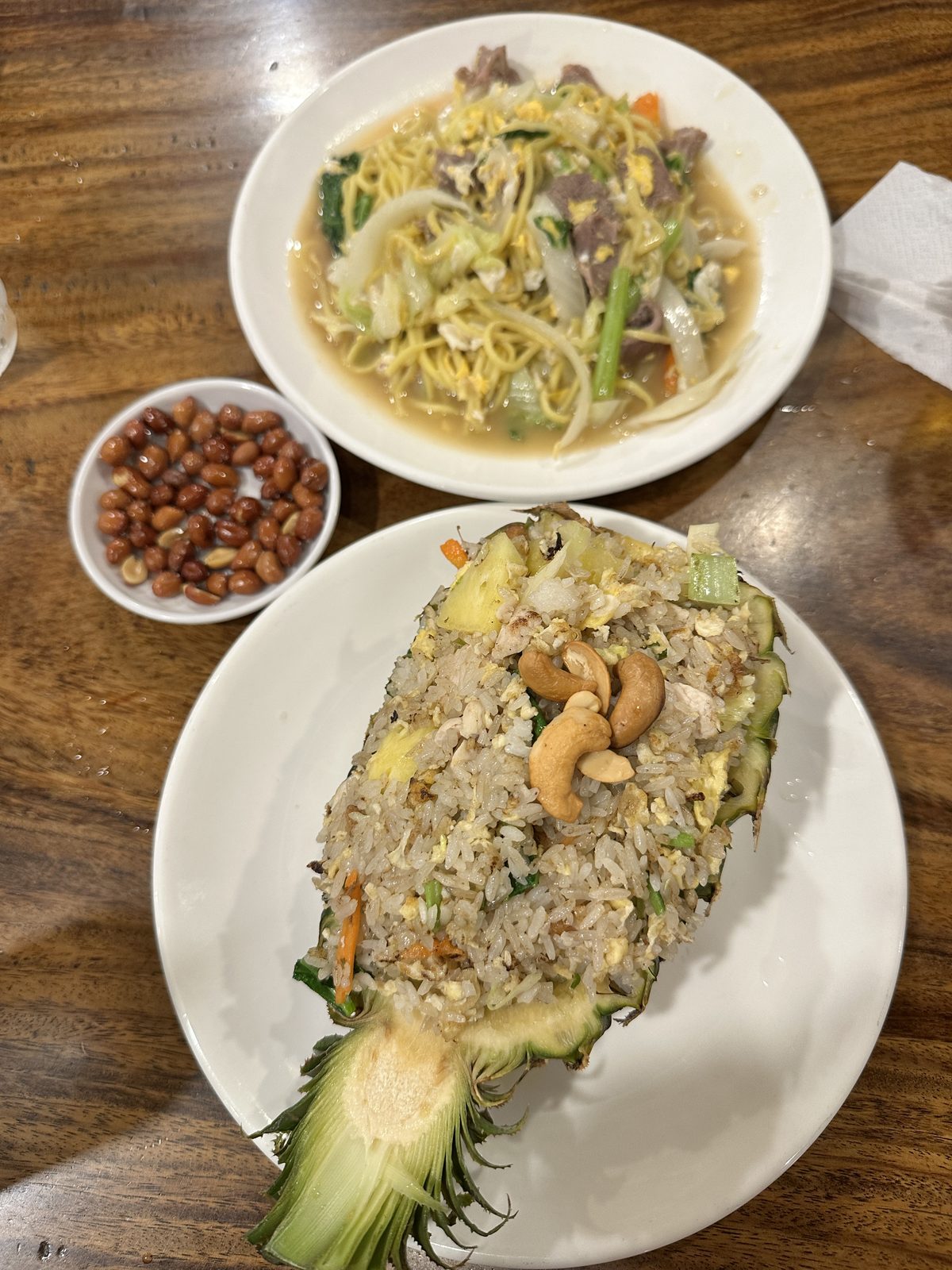 A Siem Reap dinner of beef noodles and pineapple fried rice served in a carved pineapple half, with a dish of peanuts