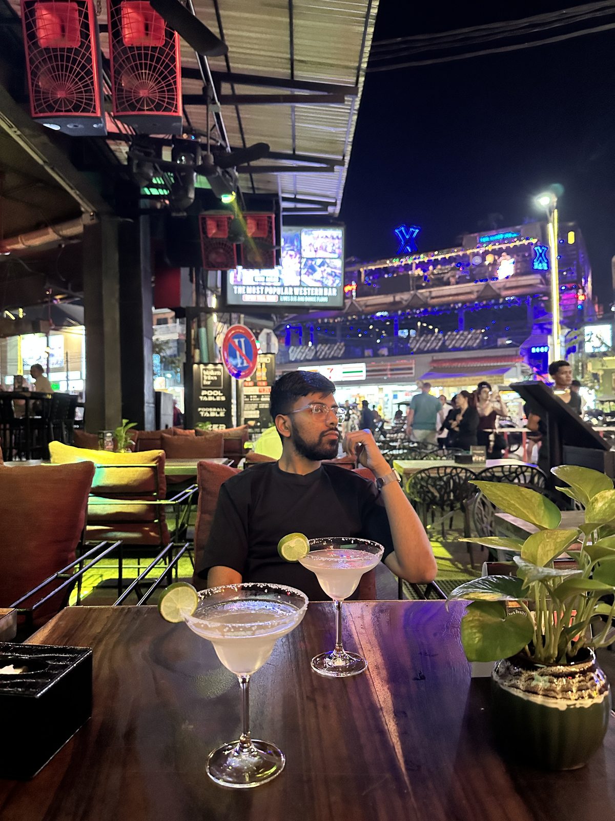 Two margaritas on a table with the neon of Pub Street bars behind