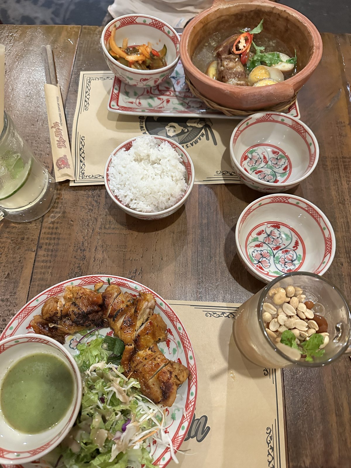 A Saigon table with clay pot braised pork and eggs, rice, grilled chicken, salad and peanuts