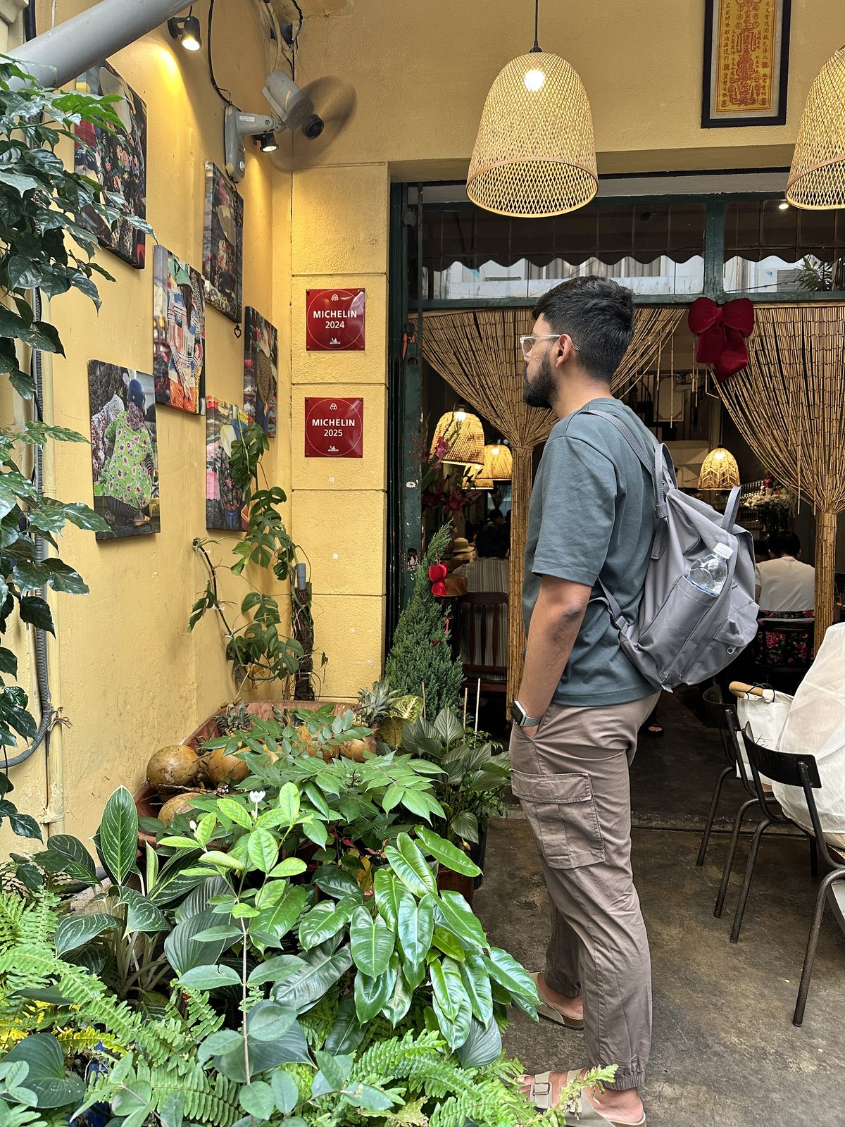 A man standing outside a restaurant entrance with Michelin 2024 and 2025 plaques on a yellow wall