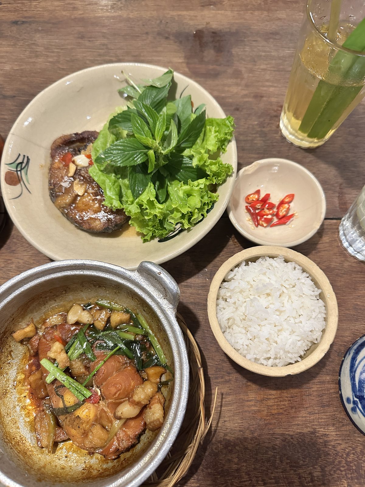 A clay pot of caramelised fish with rice, fresh herbs and sliced chilli