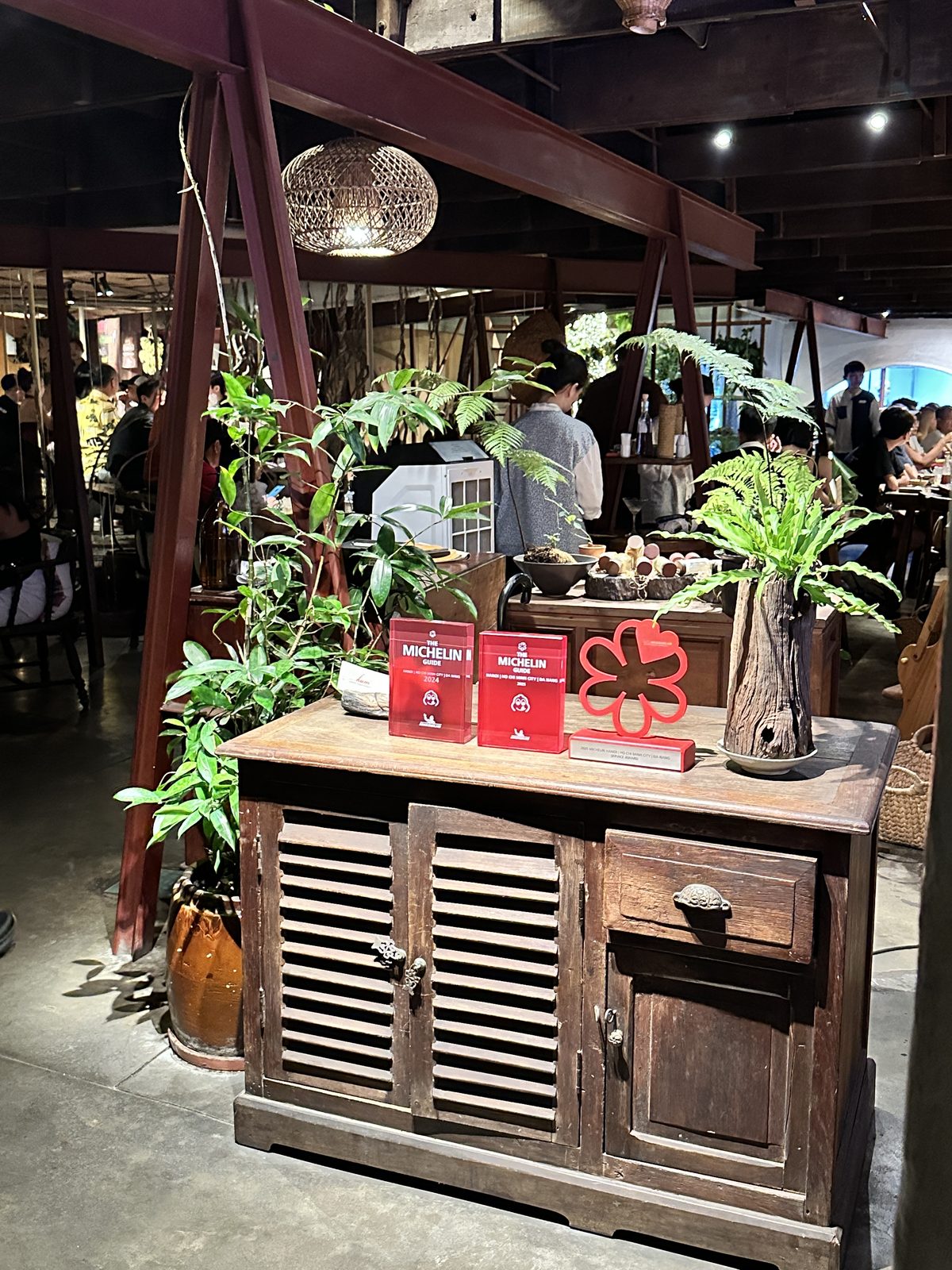 Michelin Guide 2024 and 2025 plaques and a red Michelin service award on a wooden cabinet in a restaurant