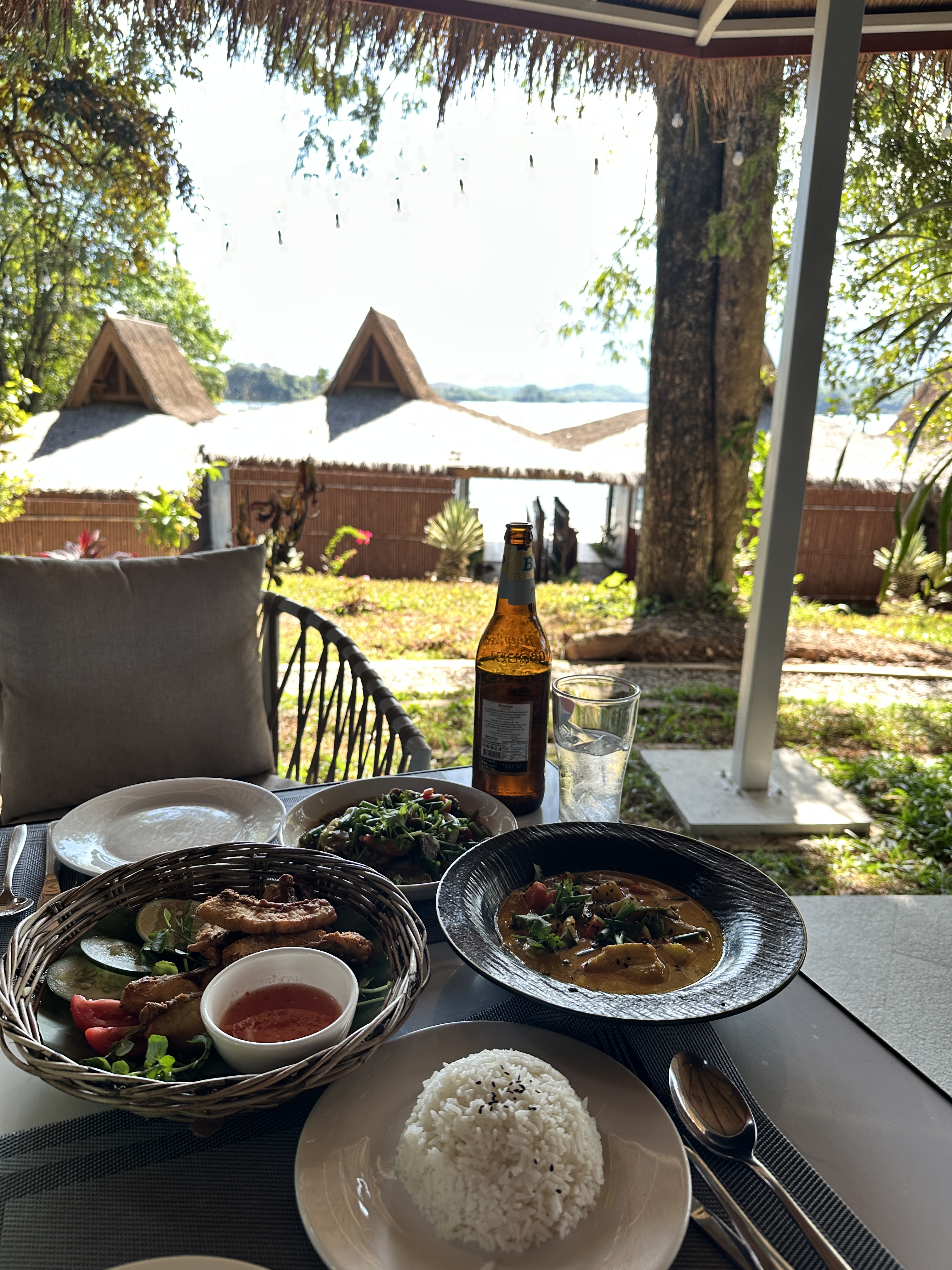 Lunch on a deck over Nam Ngum lake — curry, a basket of fried fish, greens, sticky rice and a bottle of Beerlao