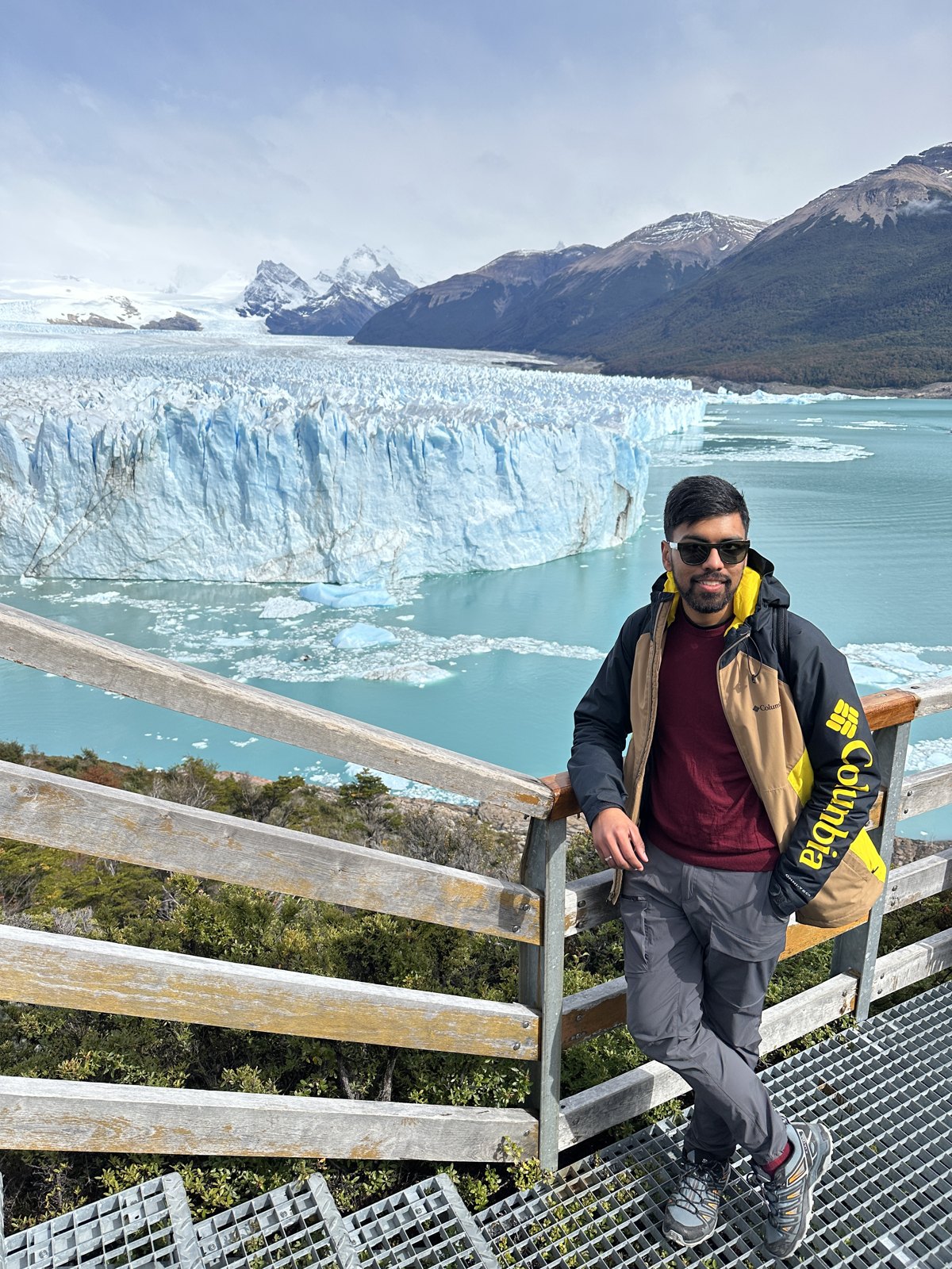 A man on the steel boardwalks in front of the Perito Moreno glacier, the ice face and floating icebergs behind him