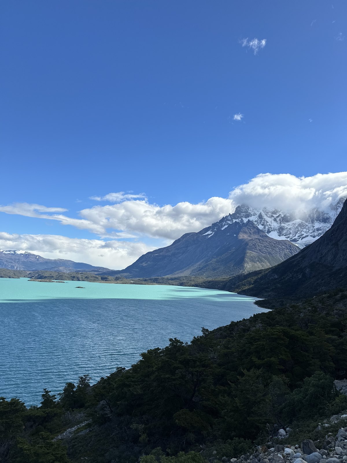 A wide view of the turquoise water of Lago Nordenskjold with mountains and cloud beyond