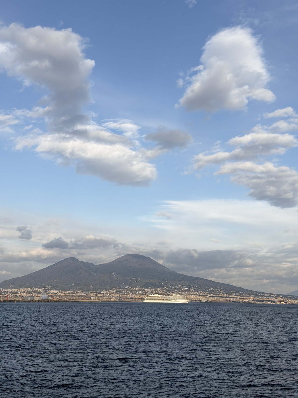 The double summit of Mount Vesuvius seen across the Bay of Naples with a cruise ship in front of it