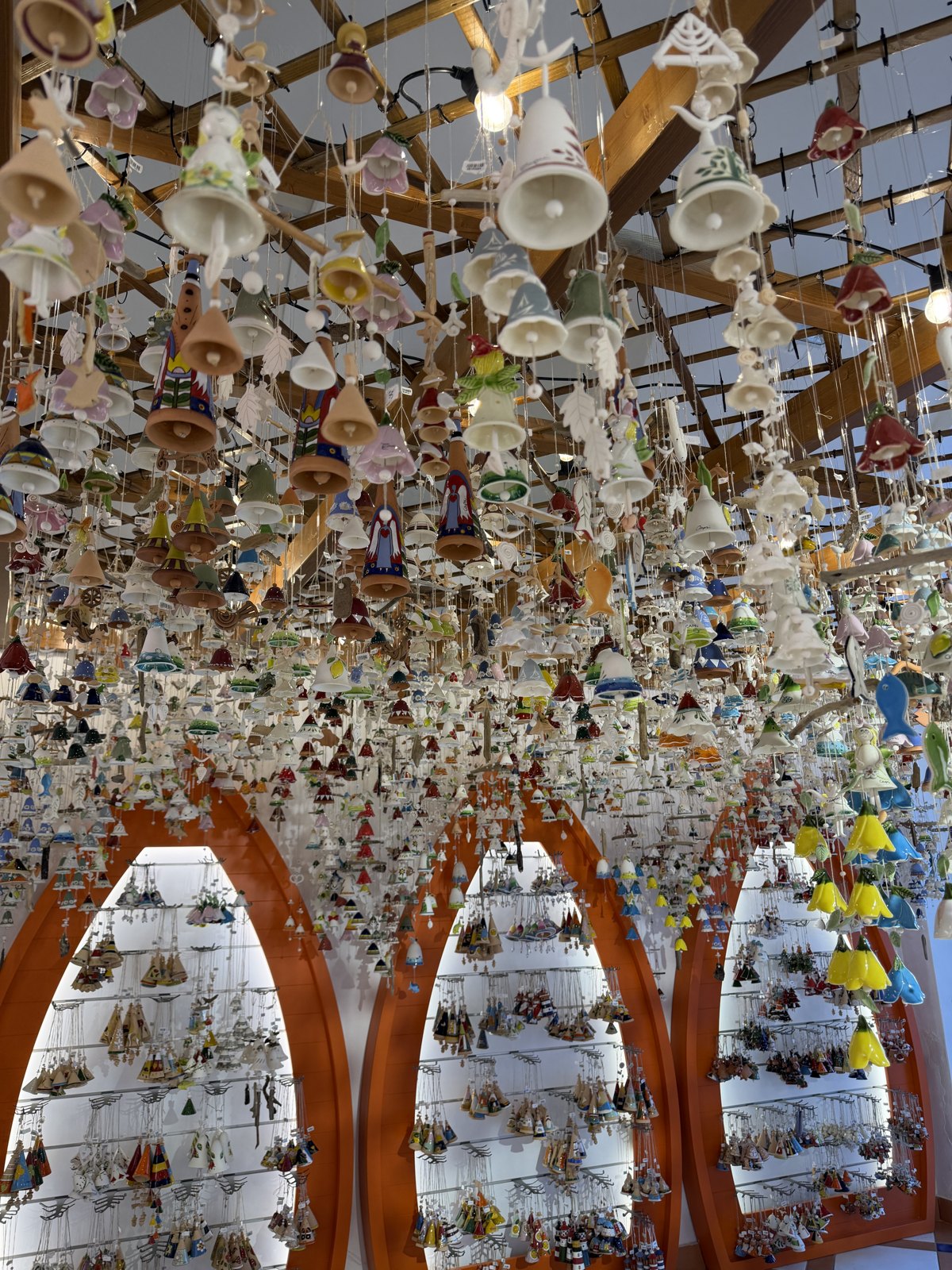The interior of a shop with hundreds of small painted ceramic bells hanging from the ceiling in rows