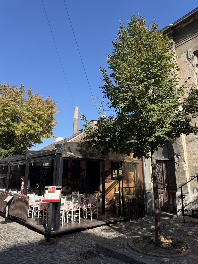 A traditional restaurant terrace with white chairs on a cobbled street corner in old Belgrade