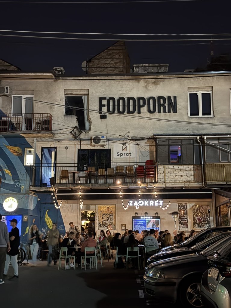 A busy street of bars at night with crowded outdoor tables under string lights