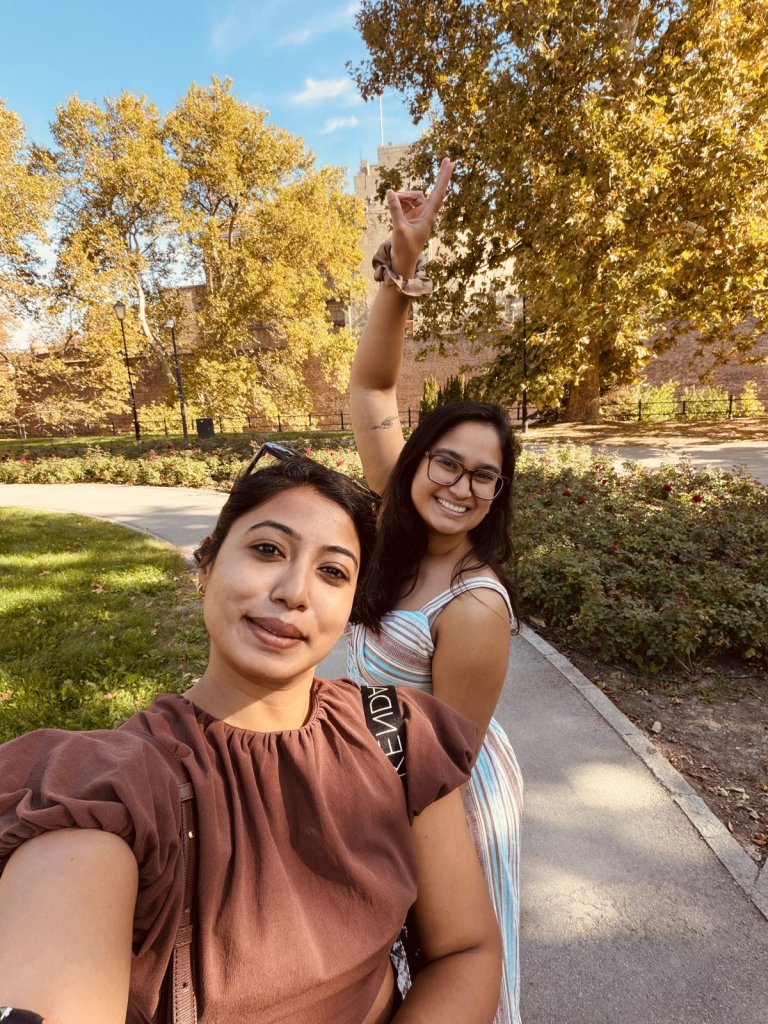 Two friends taking a smiling selfie in Kalemegdan park under autumn trees