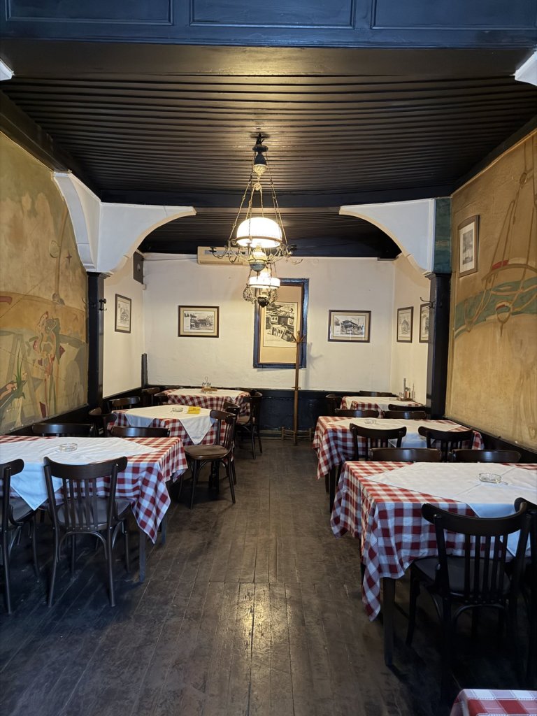 An old-style kafana dining room with red checked tablecloths