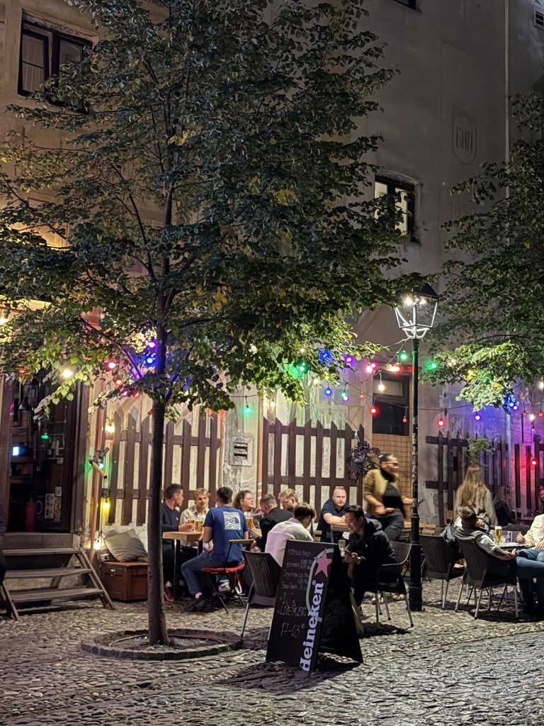 Outdoor tables under string lights on a cobbled street at night