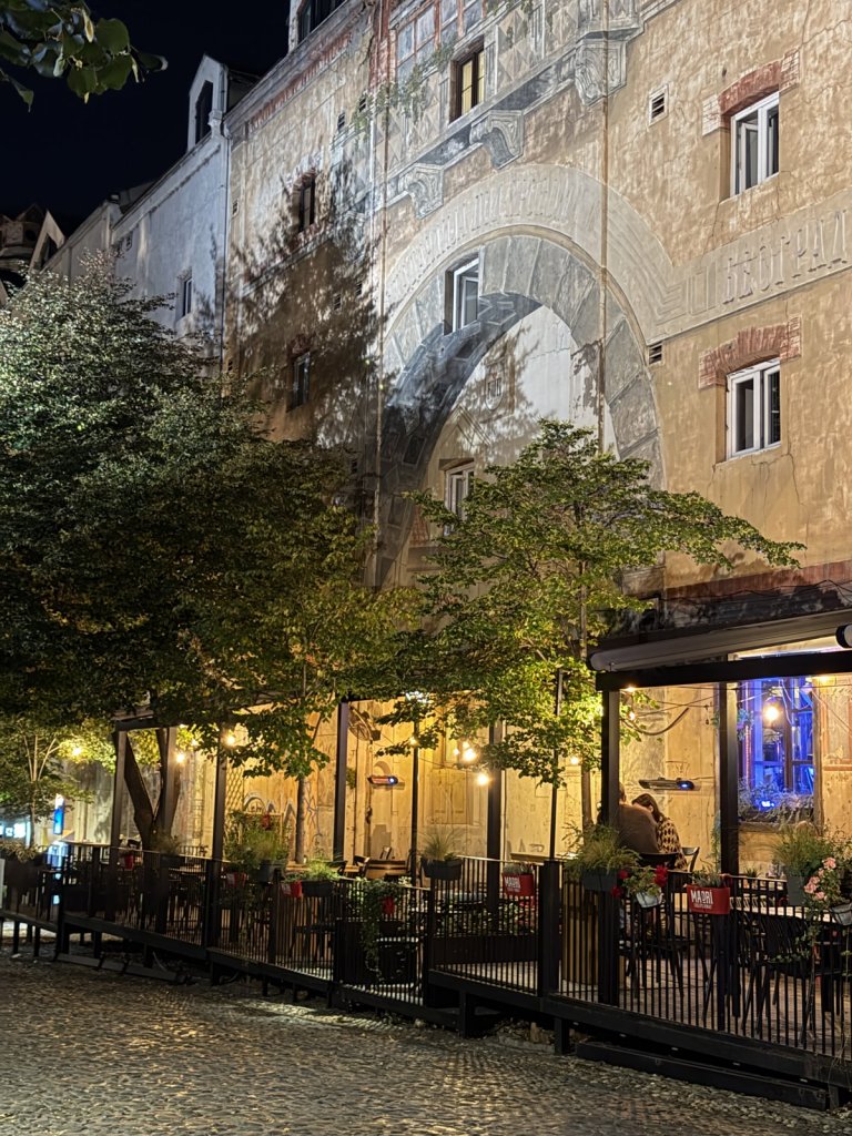 Lit facades and terraces along a cobbled street at night